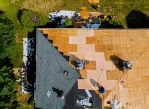 Close-up of a roofer inspecting metal roofing panels beside architectural asphalt shingles.