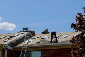 A homeowner examines a damaged roof vent and small attic entry gap with a flashlight.